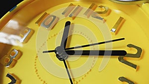 Yellow clock with black arrows running in a circle, close-up.