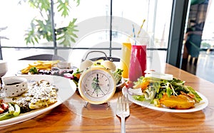 Yellow clock with a healthy food and drink background for a dinnertime with Intermittent fastin concept