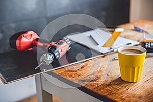 Yellow coffee mug and power drill on the table