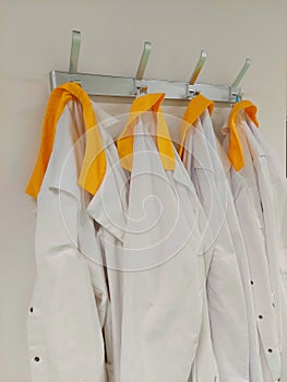 Yellow collar labcoats on coat rack