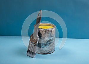 Yellow color emulsion paint tin with new brush. Home renovation concept or paint mockup with blue banner