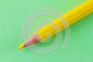 Yellow color pencil on green color paper arranged diagonally