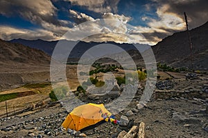 Yellow color tent being set up by trekkers for night stay in ladakh photo