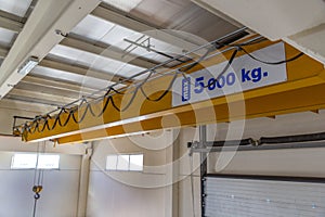 Yellow colored heavy load handling crane mounted on the ceiling ready to use in the closed warehouse area