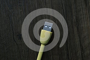 Colored USB type cable staying on dark wooden table.