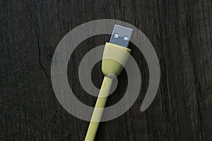 Colored USB type cable staying on dark wooden table.