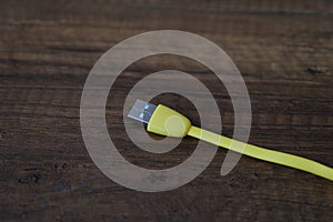Colored USB type cable staying on dark wooden table.