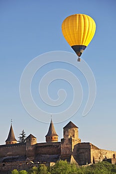 Yellow colorful hot air balloon flying in blue sky over roofs of city