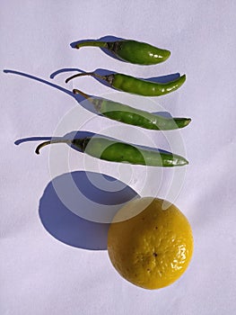 Yellow coloured lemon on white background with chillies.