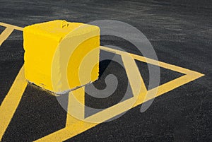 Yellow concrete block pointing lines asphalt