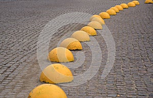 Yellow concrete hemisphere - anti-parking stop on old paving stones of square