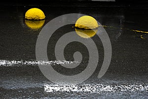 Yellow concrete hemispheres on wet asphalt.