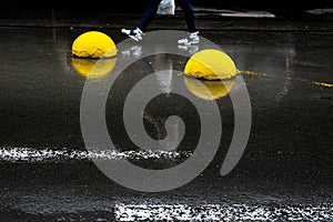 Yellow concrete hemispheres on wet asphalt.