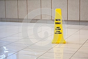 Yellow cone cautioning for wet floor in english and spanish in the hotel