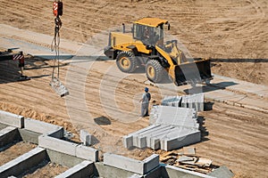 Yellow construction bulldozer at a construction site during work shot by a drone