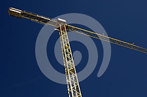 Yellow construction crane reaching clear blue sky