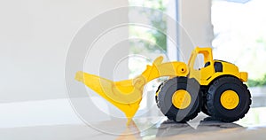 A yellow construction Loader toy vehicle with articulated parts built with sturdy plastic is placed on a table