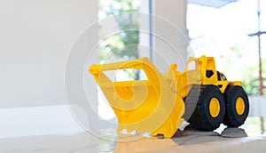 A yellow construction Loader toy vehicle with articulated parts built with sturdy plastic is placed on a table