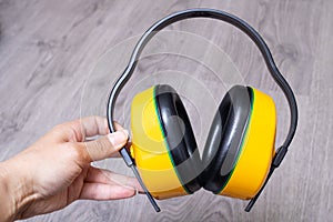 Yellow construction noise-cancelling headphones in hand closeup