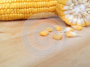 Yellow corn and corn kernels on wooden table.