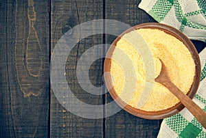 Yellow corn flour in a ceramic bowl on a rustic wooden table. In