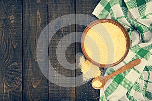 Yellow corn flour in a ceramic bowl on a rustic wooden table. Ingredients for preparation of a Italian traditional Polenta