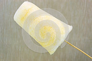 Yellow cotton sweet candy in wooden stick on light coloured background