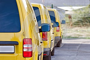 Yellow courier or taxi cars are lined up in parking lot.