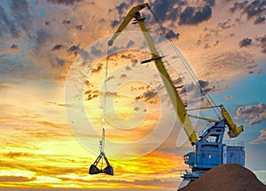 Yellow crane in cargo port translating coal. Industrial scene