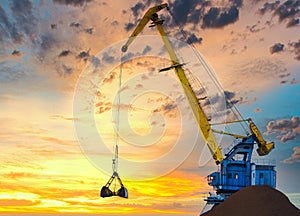 Yellow crane in cargo port translating coal. Industrial scene