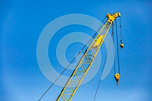 Yellow crane jib hoist against blue sky