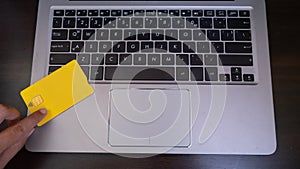 Yellow Credit Card On Laptop Computer Keyboard.Consumer making an Online shopping and purchase in internet paying with debit card