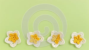 Yellow crocheted flowers row pattern on a green background