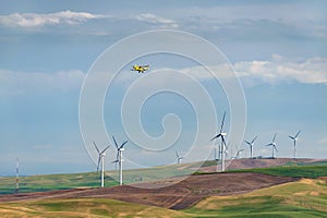 Yellow Crop Duster Flying Over a Wind Farm in Eastern Washington.