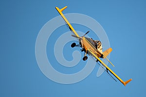 Yellow Crop Dusting Plane Flying in a Blue Sky