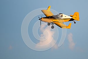 Yellow Crop Dusting Plane Flying in a Blue Sky photo