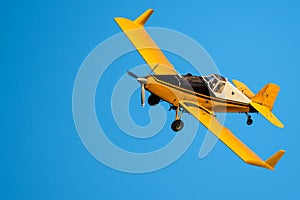 Yellow Crop Dusting Plane Flying in a Blue Sky