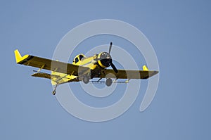 Yellow Crop Dusting Plane Flying in a Blue Sky