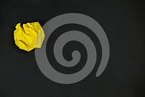 Yellow crumpled paper ball on a black background