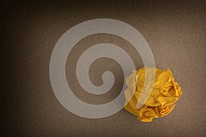 Yellow crumpled paper ball on a brown background