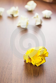 Yellow crumpled paper ball on dark brown wood table with group o