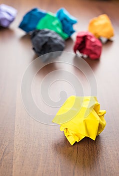 Yellow crumpled paper ball on dark brown wood table with group o