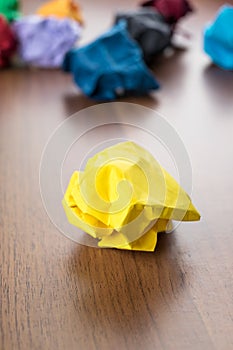 Yellow crumpled paper ball on dark brown wood table with group o