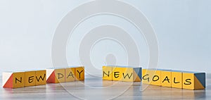 On the yellow cubes lying on the log table inscription: `New day. New goals
