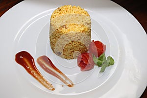 Yellow Cup rice decoration with tomato sauce and make tomato flower on white plate on table