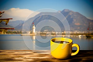 Yellow cup with tea on wooden table opposite a defocused backgr photo