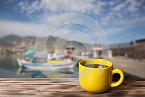 Yellow cup with tea on wooden table opposite a defocused backgr photo