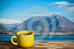 Yellow cup with tea on wooden table opposite a defocused backgr photo