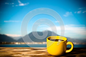 Yellow cup with tea on wooden table opposite a defocused backgr photo