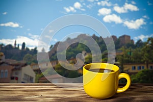 Yellow cup with tea on wooden table opposite a defocused backgr photo